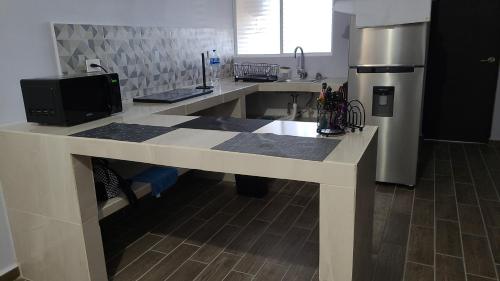 a kitchen with a large white counter with a refrigerator at recamara en Departamento amueblado in Monterrey