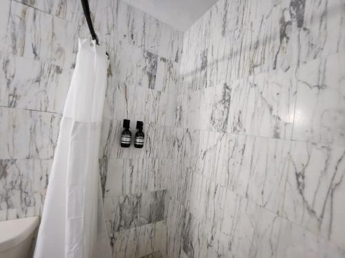 Un baño con paredes de mármol blanco y cortina de ducha. en Selva Boutique Hotel - Luquillo Oceanfront Retreat - Adults Only, en Luquillo