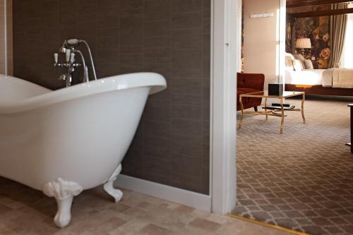a white bath tub in a bathroom with a bedroom at Glenesk Hotel in Edzell