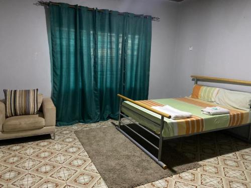 a bedroom with a bed and a green curtain at Fajara Suites, Bakau, Banjul, Gambia in Banjul