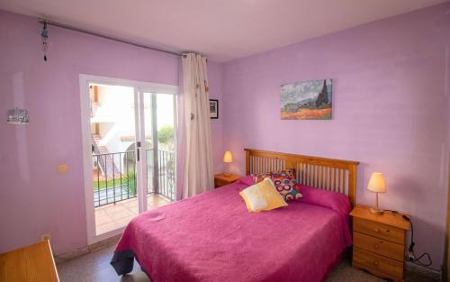een slaapkamer met een roze bed en een balkon bij Primera línea Playa Romana - Habitat 12 ALBERT VILLAS in Alcossebre