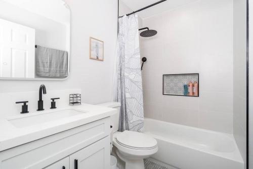 a white bathroom with a toilet and a shower at Hawaii Dream Escape! Steps from the Sand in Hauula