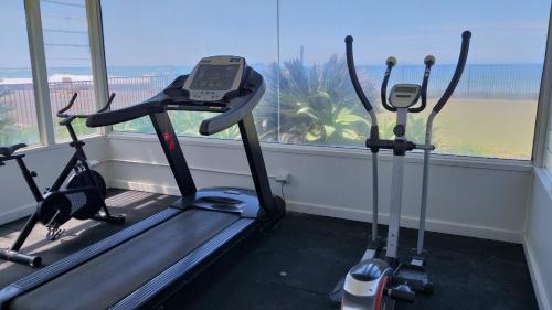 a gym with three exercise bikes in front of a window at Private Suite Nautilus Beach Front Resort in Coffs Harbour