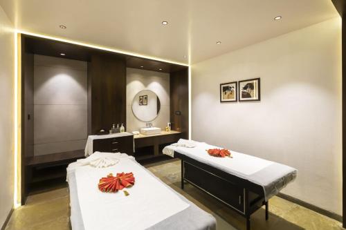 two beds in a room with a sink and a mirror at Ramee International Surat in Surat