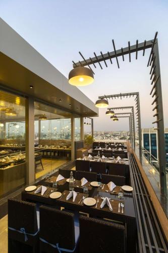 a restaurant with a long table on the roof of a building at Ramee International Surat in Surat