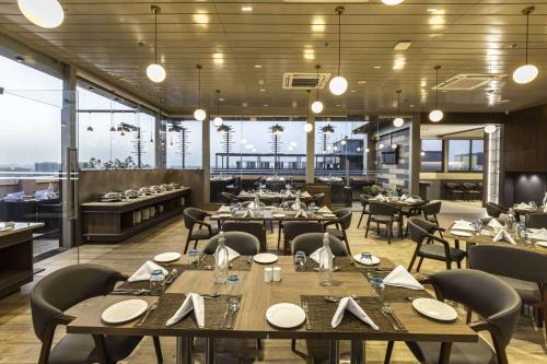 a restaurant with tables and chairs and large windows at Ramee International Surat in Surat