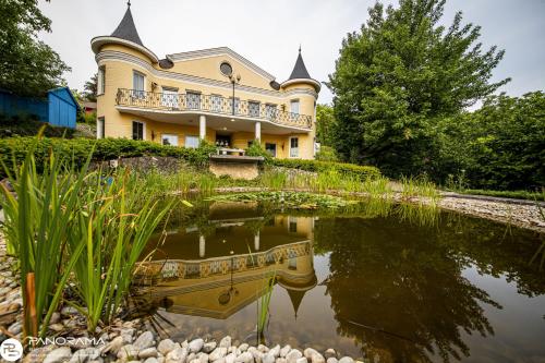 a large house with a pond in front of it at Panoráma Birtok - Wellness Panzió, Konferencia és Rendezvényközpont in Győrújbarát