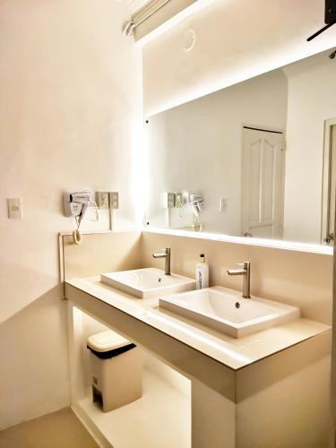 a bathroom with two sinks and a large mirror at NomadsMNL Hostel in Manila