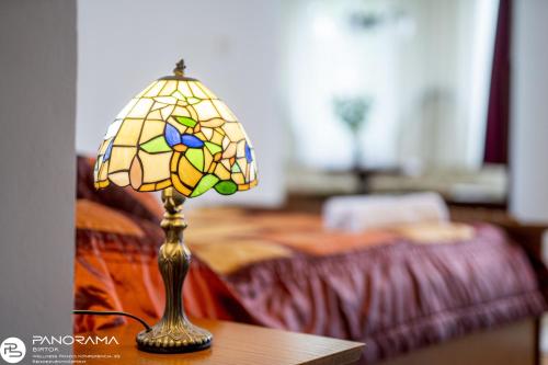 a lamp on a table next to a bed at Panoráma Birtok - Wellness Panzió, Konferencia és Rendezvényközpont in Győrújbarát