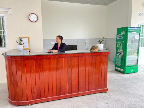 a woman sitting at a wooden bar in a room at NHÀ NGHỈ HOÀNG GIA - TT Lai Vung in Lai Vung