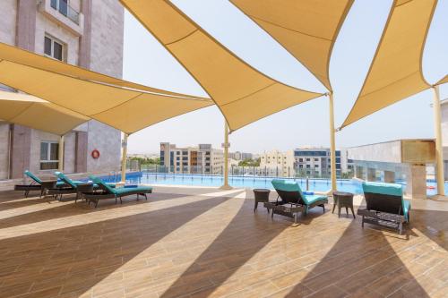 a patio with yellow umbrellas and chairs and a pool at Levatio Suites Muscat, a member of Radisson Individuals in Muscat