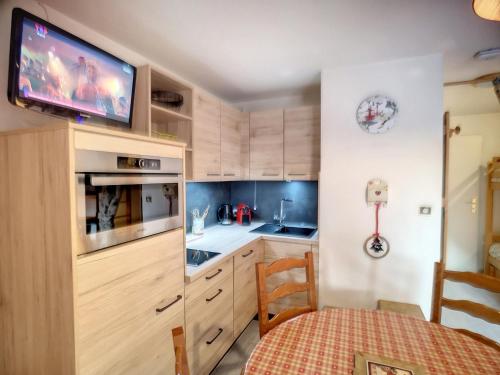Il comprend une cuisine avec des placards en bois et une télévision murale. dans l'établissement Les Menuires: 2 Pièces, 4 Pers, Pied des Pistes, Parking Gratuit - FR-1-178-100, aux Menuires