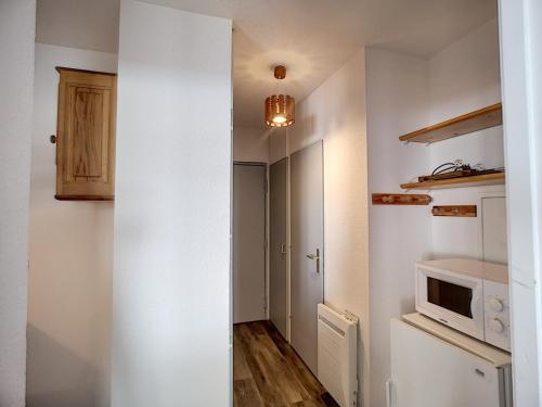 une petite cuisine avec un four micro-ondes et un couloir dans l'établissement 3 pièces 6 pers aux Bruyères - Animaux admis, parking et balcon - FR-1-178-104, aux Menuires