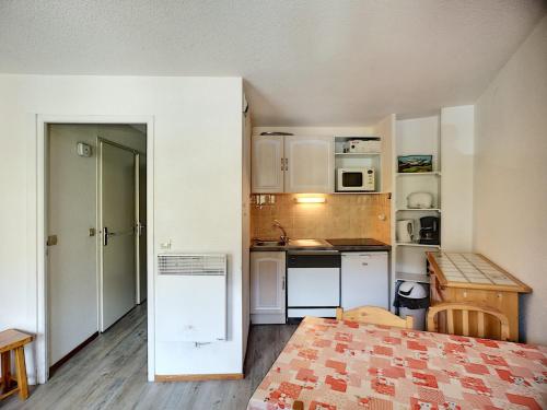 une petite cuisine avec des armoires blanches et une table dans l'établissement Studio cabine 4 pers, ski aux pieds, carrefour central, PARKING - FR-1-178-105, aux Menuires