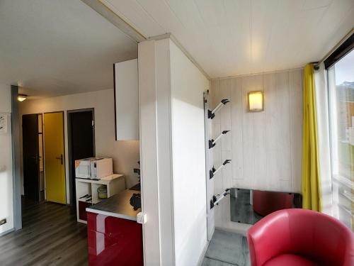une chambre avec une chaise rouge et une cuisine dans l'établissement Appartement rénové 2 pièces, 4 pers, WIFI, pied des pistes, à proximité commerces - FR-1-178-125, aux Menuires