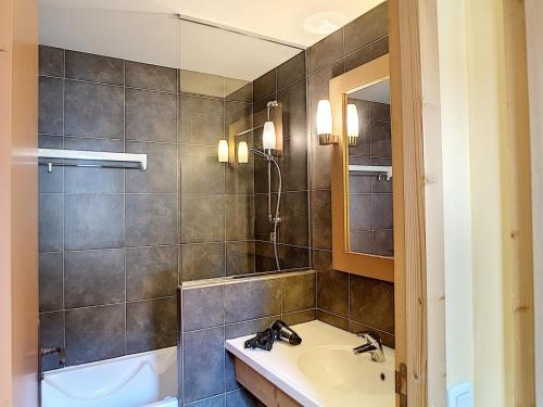 uma casa de banho com um lavatório, uma banheira e um espelho. em Appartement Les Menuires, 2 pièces, 5 personnes - FR-1-178-291 em Les Menuires