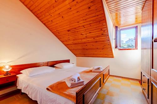 a bedroom with a large bed with a wooden ceiling at Apartmani Antula in Prigradica