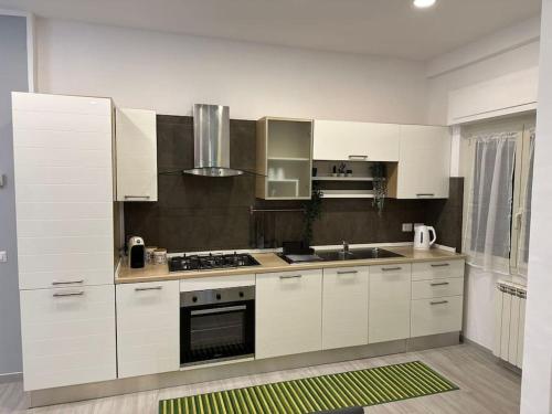 a kitchen with white cabinets and a stove top oven at Simply House Civitavecchia in Civitavecchia