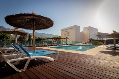 een zwembad met 2 ligstoelen en een parasol bij Beautiful flat with a wonderful view close to the beach in Marbella