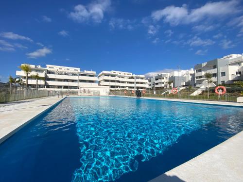 a swimming pool with blue water in front of buildings at Zen Apartment Estepona in Estepona