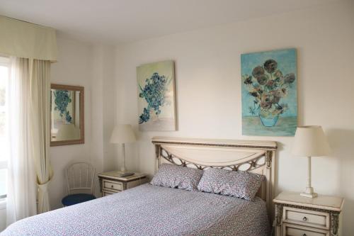 a bedroom with a bed and two lamps and paintings at Apartment 10 minutes walk from Puerto Banus in Marbella