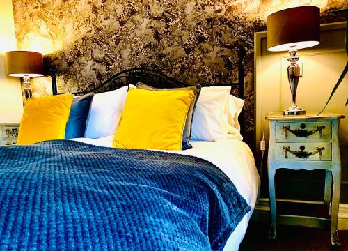 a bedroom with a bed with blue and yellow pillows at The Capon Tree Town House in Jedburgh