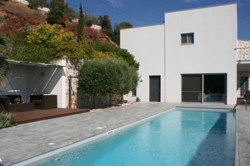 a swimming pool in front of a white house at Villa Nafsika stunning view on the Aegean Sea in Áyioi Apóstoloi