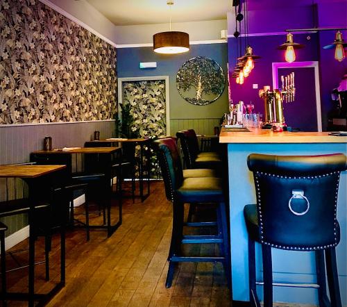 a bar with black chairs and purple walls in a restaurant at The Capon Tree Town House in Jedburgh