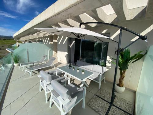 a patio with a table and chairs and an umbrella at Zen Apartment Estepona in Estepona