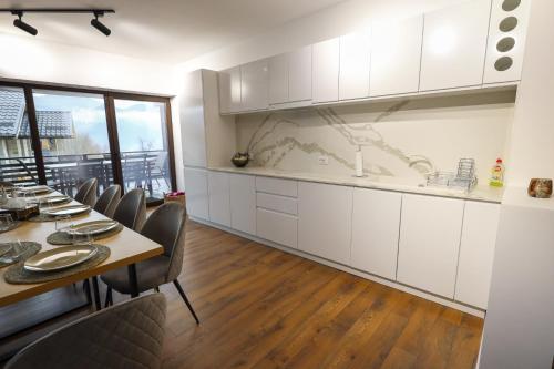 a kitchen with white cabinets and a table and chairs at Pensiunea CityView in Câmpulung Moldovenesc