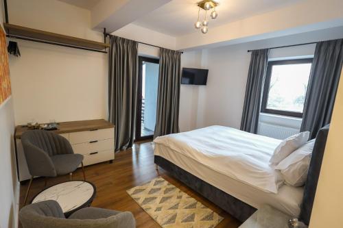 a bedroom with a bed and a desk and two chairs at Pensiunea CityView in Câmpulung Moldovenesc