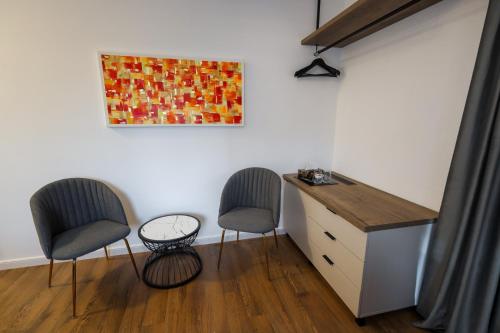 a room with two chairs and a dresser and a painting at Pensiunea CityView in Câmpulung Moldovenesc