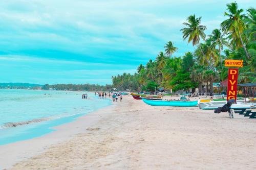 a beach with boats and people on the water at Rea Beach Way Hotel in Trincomalee