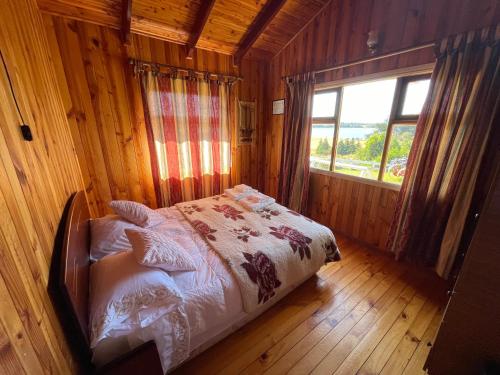a bed in a wooden room with a window at Cabañas Sol Del Mar in Ancud