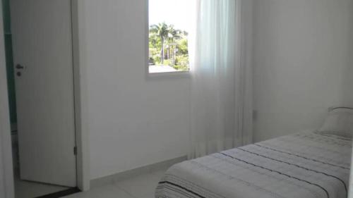 Habitación blanca con cama y ventana en Apartamento na bacutia com 3 suites e varanda, en Guarapari