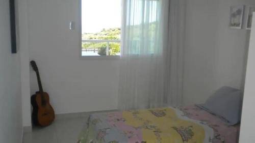 Un dormitorio con una cama y una guitarra en una habitación en Apartamento na bacutia com 3 suites e varanda, en Guarapari