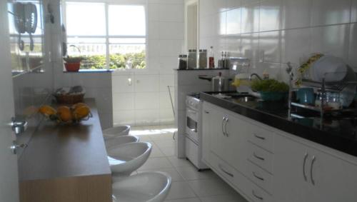 una cocina con encimeras blancas y taburetes blancos. en Apartamento na bacutia com 3 suites e varanda, en Guarapari