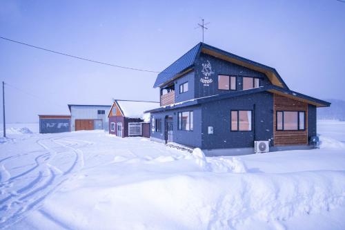 a house is covered in snow in a yard at Yadoya YADOKARI in Pippu