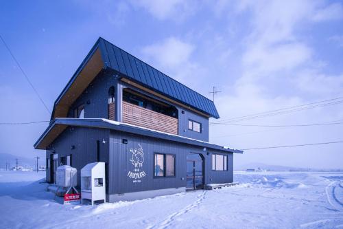 a blue building in the snow next to a street at Yadoya YADOKARI in Pippu