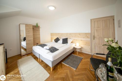 1 dormitorio con cama blanca y espejo en Panoráma Birtok - Wellness Panzió, Konferencia és Rendezvényközpont, en Győrújbarát