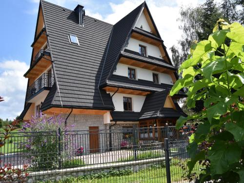 a large house with a black roof at Pokoje Gościnne Budzowie in Czarna Góra