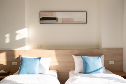 two beds in a hotel room with blue pillows at 161 Easy Inn in Yuchi