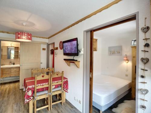 Cette chambre comprend une table, un lit et une télévision. dans l'établissement Appartement 2 Pièces + Coin Montagne, Terrasse, 5 Pers, Skis aux Pieds - Les Bruyères, Les Menuires - FR-1-178-88, aux Menuires