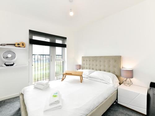 a white bedroom with a large bed and a window at Pass the Keys Sleek 1 Bed Apartment w Parking in Cardiff