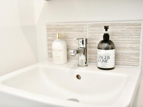 a bathroom sink with two bottles of wine on it at Pass the Keys Sleek 1 Bed Apartment w Parking in Cardiff