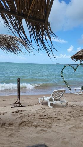 a beach with a white lounge chair on the beach at Casa Recanto das Mangueiras Japaratinga - Alagoas in Japaratinga