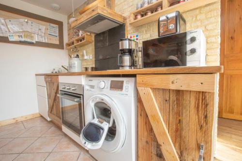 a kitchen with a washing machine and a microwave at Ecolodge ENTRE MER & CAMPAGNE - Maison d'Hôtes POMME DE PAILLE - Entre Honfleur et Etretat in Octeville-sur-Mer