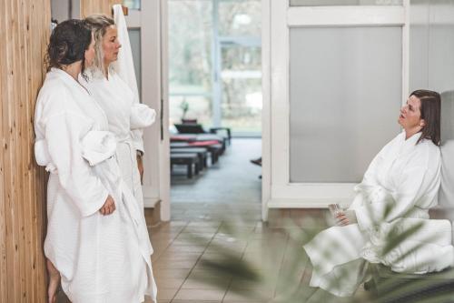 two women in white robes looking in a mirror at Wellness- & Sporthotel Haus am See in Arendsee