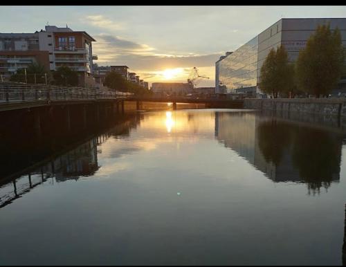 a river in a city with the sun setting at Appartement haut standing F2 Rivetoile Strasbourg centre parking gratuit terrasse in Strasbourg
