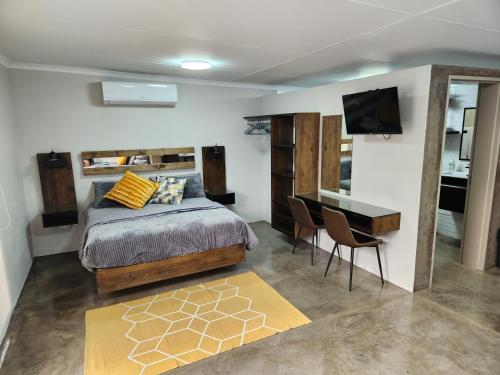 Schlafzimmer mit einem Bett, einem Schreibtisch und einem TV in der Unterkunft Die Stoor in Upington